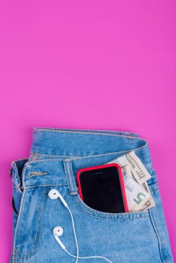 Mavi kot, arka cebinde pembe arka planda müzik için kulaklıklı bir telefon..