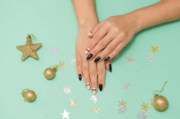 Beautiful female manicure on a colored background with a festive element. Holiday content.