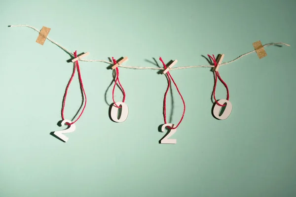 New Year's content 2020 numbers on red strings are half-hung, on a mint background. — Stock Photo, Image