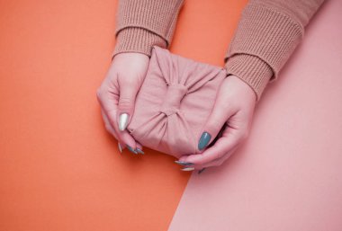 Güzel manikürlü kadın ellerinde bir hediye. Ekolojik Paketleme Hediyesi - Furoshiki.