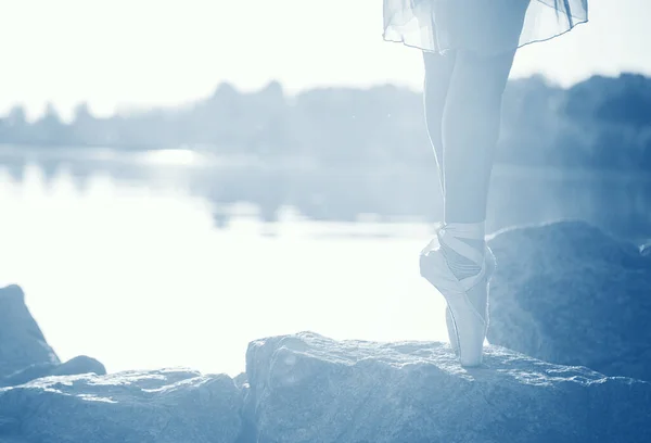 Ноги женщины на берегу моря на камнях, на закате, в тонированном цвете года . — стоковое фото