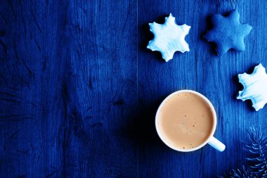 Ahşap bir masada, üzerinde zencefilli ekmek ve mavi tonlu nefis aromatik latte kahve.