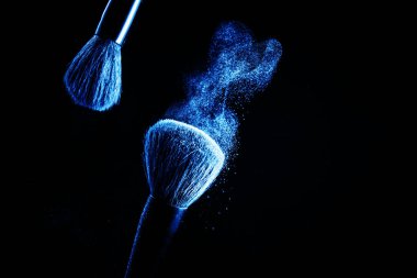 Siyah arkaplanda mavi pudra ile makyaj fırçası