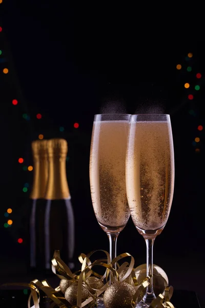 Två vackra champagneglas är fyllda med blanka leksaker. Serpentin och ljus — Stockfoto