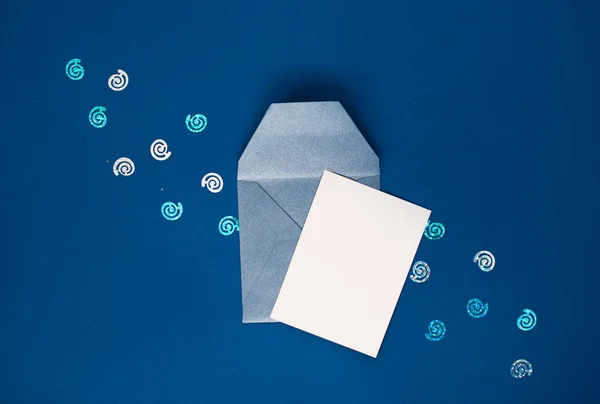 Белая открытка в маленьком голубом конверте, на синем фоне с блецком . — стоковое фото