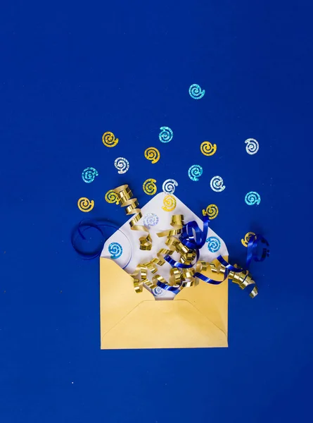 Hermoso sobre de perlas amarillas con lentejuelas y serpentina sobre un fondo azul . — Foto de Stock