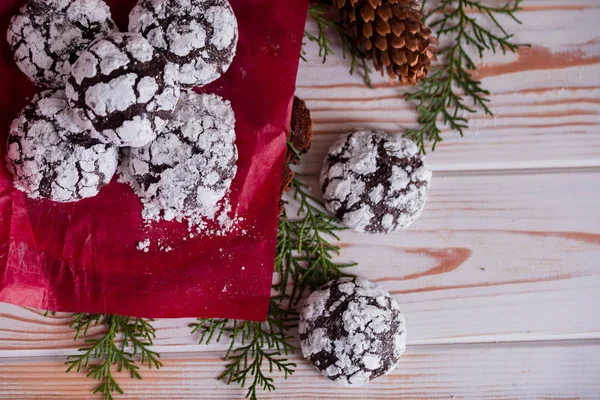 Tasty and fragrant chocolate chip cookies are crushed with powdered sugar, with multi-colored lights on the table. Merry Christmas — Stock Photo, Image