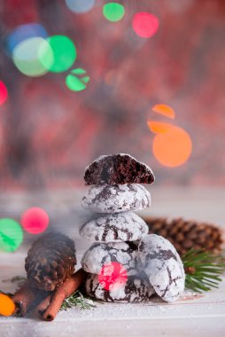Lezzetli ve kokulu çikolatalı kurabiyeler, masanın üzerinde çok renkli ışıklarla pudra şekeriyle ezilir. Mutlu Noeller.