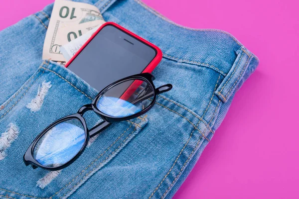 Banner on pink background with blue jeans, money, headphones, 5g internet phone, glasses.