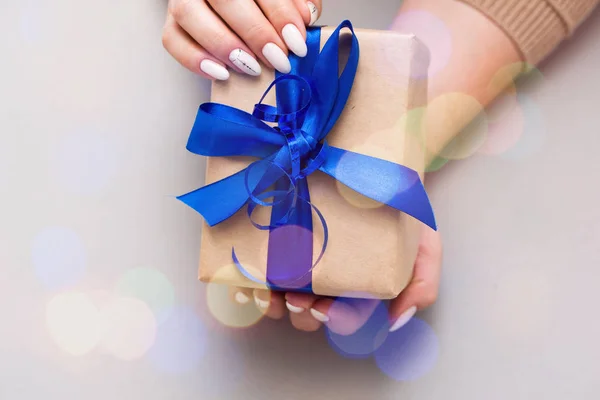 Bela manicure feminina elegante em um fundo cinza com presente na mão . — Fotografia de Stock