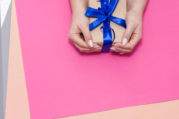 Bela manicure feminina elegante em um fundo rosa com presente na mão . — Fotografia de Stock