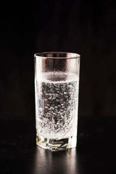 Αεριούχο νερό σε ποτήρι σε μαύρο τραπέζι και μαύρο φόντο. — Φωτογραφία Αρχείου