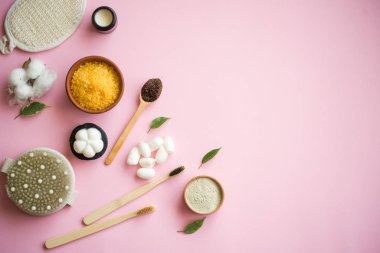 Kozmetik banyo tuzu, yüz için üzüm gomaj, pembe arka planda vücut için kahve fırçası..