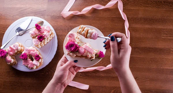 Tangan dari tukang manisan dengan lembut dan lezat kue surat. Kue dengan bunga hidup, coklat putih, kacang-kacangan. Tangan seorang koki kue, kemasan makanan penutup . — Stok Foto