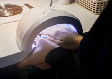 Bir kadının manikür süreci, jel cila. Çivilere, lambaya, cilaya, aletlere, tırnağa dikkat edin..