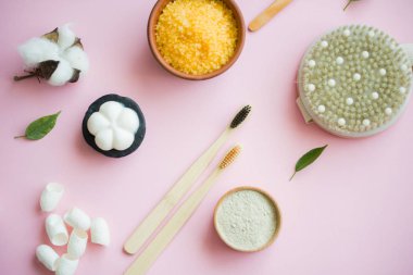 Kozmetik banyo tuzu, yüz için üzüm gomaj, pembe arka planda vücut için kahve fırçası..