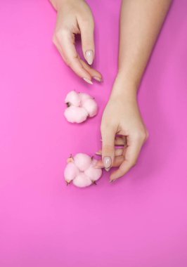 Hassas tonlarda, parlak bir arka planda, yumuşak pembe pamuklu güzel bir kadın manikürü. Yazı için yer.