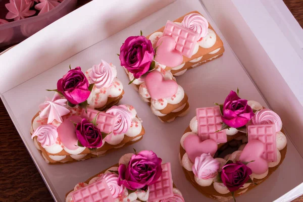 Tårta i form av bokstäver kärlek, jublad med levande blommor, pärlor, choklad hjärtan. — Stockfoto