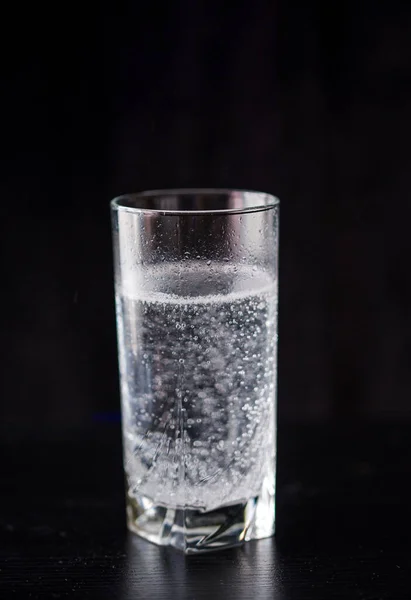 Ένα ποτήρι νερό τελευταίας τεχνολογίας σε ένα ψηλό ποτήρι σε μαύρο φόντο. Ισορροπία. — Φωτογραφία Αρχείου