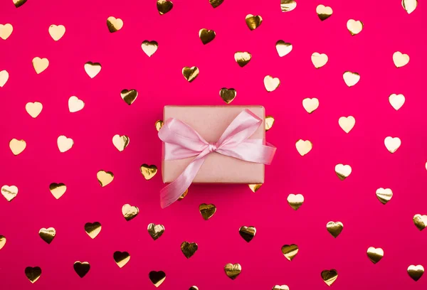 Kotak hadiah yang indah dengan pita satin warna merah muda halus, dengan emas confetti . — Stok Foto