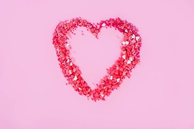 Pembe arka planda küçük tatlı kalplerden oluşan büyük bir kalp..