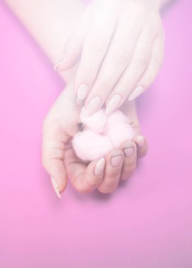 Zarif tonlarda, parlak bir arka planda, yumuşak pembe pamuklu güzel bir kadın manikürü..