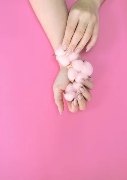 Manicure de mulheres bonitas em tons delicados, em um fundo brilhante com algodão suavemente rosa . — Fotografia de Stock