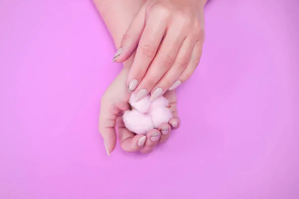 Manicure de mulheres bonitas em tons delicados, em um fundo brilhante com algodão suavemente rosa . — Fotografia de Stock