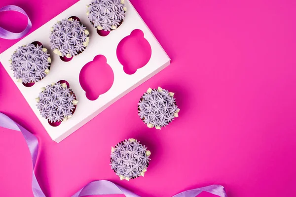 Deliziosi cupcake shawn con crema di cagliata sotto forma di fiori su uno sfondo rosa . — Foto Stock