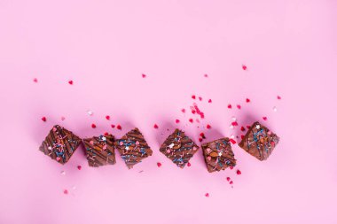 İçinde badem olan çikolatalı kek, pembe arka planda festival tozu. Yukarıdan görüntüle