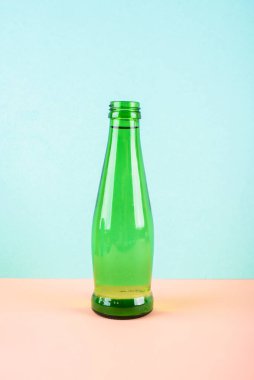 Cam bir su şişesi açık arkaplanda parlak yeşildir. Metin için bir yer.