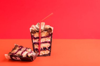 Tatlı olarak bir bardak buzlu içecek ve kırmızı arka planda bir tüp. Karamel, pasta, krema, çikolata.