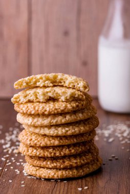 Yuvarlak susamlı kurabiyeler, masada süt ve meyve suyu. Pişirmek için susam tohumları