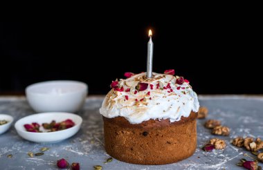 Paskalya pastası çok güzel dekore edilmiş ve mumla süslenmiş. Beton zeminde beyaz çatal bıçak.