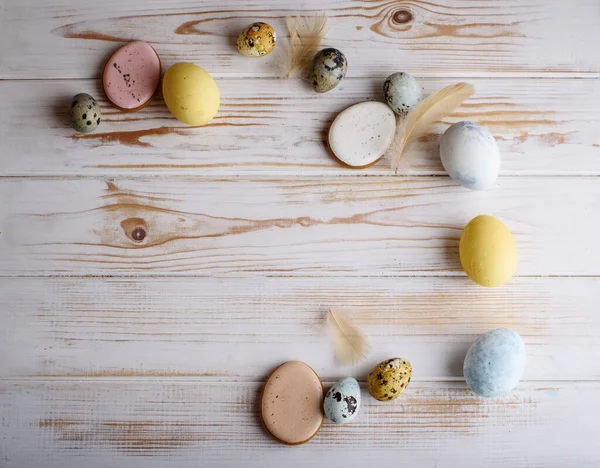 Beautiful Easter composition of eggs with natural colors, gingerbread, flowers, feathers. Holiday content.