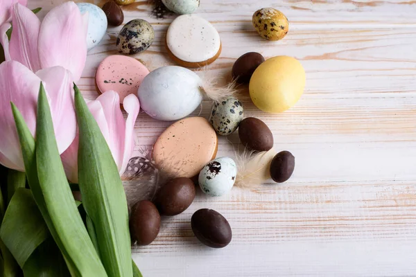 Beautiful Easter composition of eggs with natural colors, gingerbread, flowers, feathers. Holiday content.