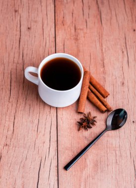 Tarçın çubukları ve siyah kaşıkla hafif arka planda mis kokulu doğal kahve..