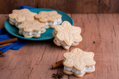 Çiçek şeklinde kremalı kurabiyeler, hafif ahşap arka planda. Lezzetli tatlılar