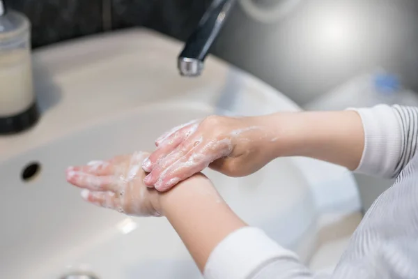 A little boy washes his hands with soap. Hand dyscentuation from viruses.
