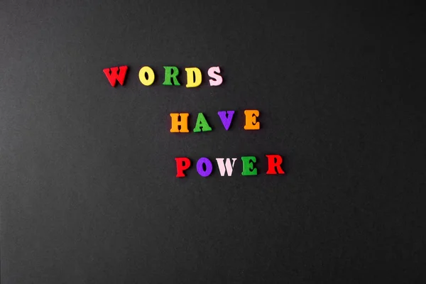 Words have the power of multicolored wooden letters on a black background.
