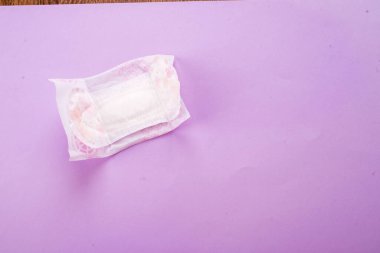 Pembe üzerine hijyenik ped, pamuk çiçekler. Kişisel bakım, kadın hijyen konsepti. Kritik günler, kan süresi, adet döngüsü.