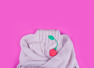 Çilekli pembe bir arka planda, narin renkte, sıcak örülmüş süveter..
