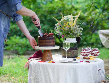 Bir bardak beyaz şarap, böğürtlen ve yabani çiçeklerle süslenmiş lezzetli çikolatalı pasta. Kırsalda piknik