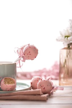 Kek, pembe çikolata kremalı ve ahşap arka planda çiçekler olan güzel bir çatal bıçakta hafif bir anahtar takar. Lezzetli yemek.