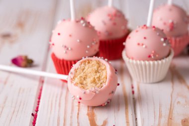 Pembe kremalı bir çubukta tatlı, ahşap bir arka planda serpiştirilmiş. Pasta çubukları tatlıların arasında kesiliyor. Lezzetli yemek.