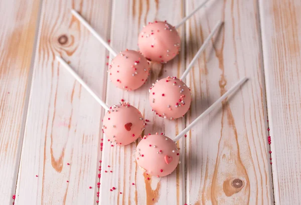 Çubukta tatlı. Ahşap zemin üzerine serpiştirilmiş pembe kek. Lezzetli yemek.