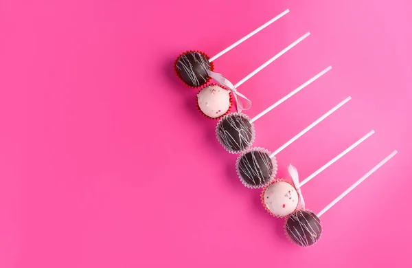 Composition of cake pops on a pink background with a different cream. Dessert on a stick. Tasty food