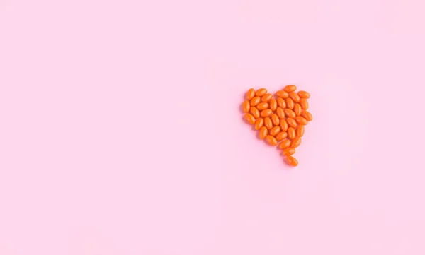 Portakal Tabletleri Pembe Arka Planda Kalp Şeklinde Cam Bir Şişeden — Stok fotoğraf