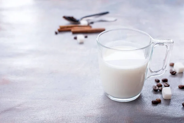 Delicioso y fragante café con una taza de vaso de leche, palitos de canela fragante, granos de café, terrones de azúcar —  Fotos de Stock