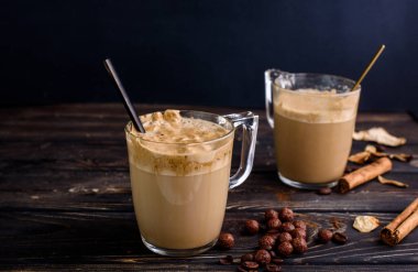 Cam bardaklarda lezzetli ve kokulu dalgona kahvesi, tarçın çubukları, kurutulmuş mantarlar, bir kaşık hazır kahve, şeker..